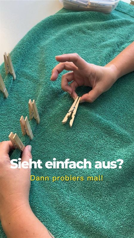Standbild aus einem Reel: Übung mit Wäscheklammern auf einem Handtuch, Texteinblendung „Sieht einfach aus? Dann probiers mal!“